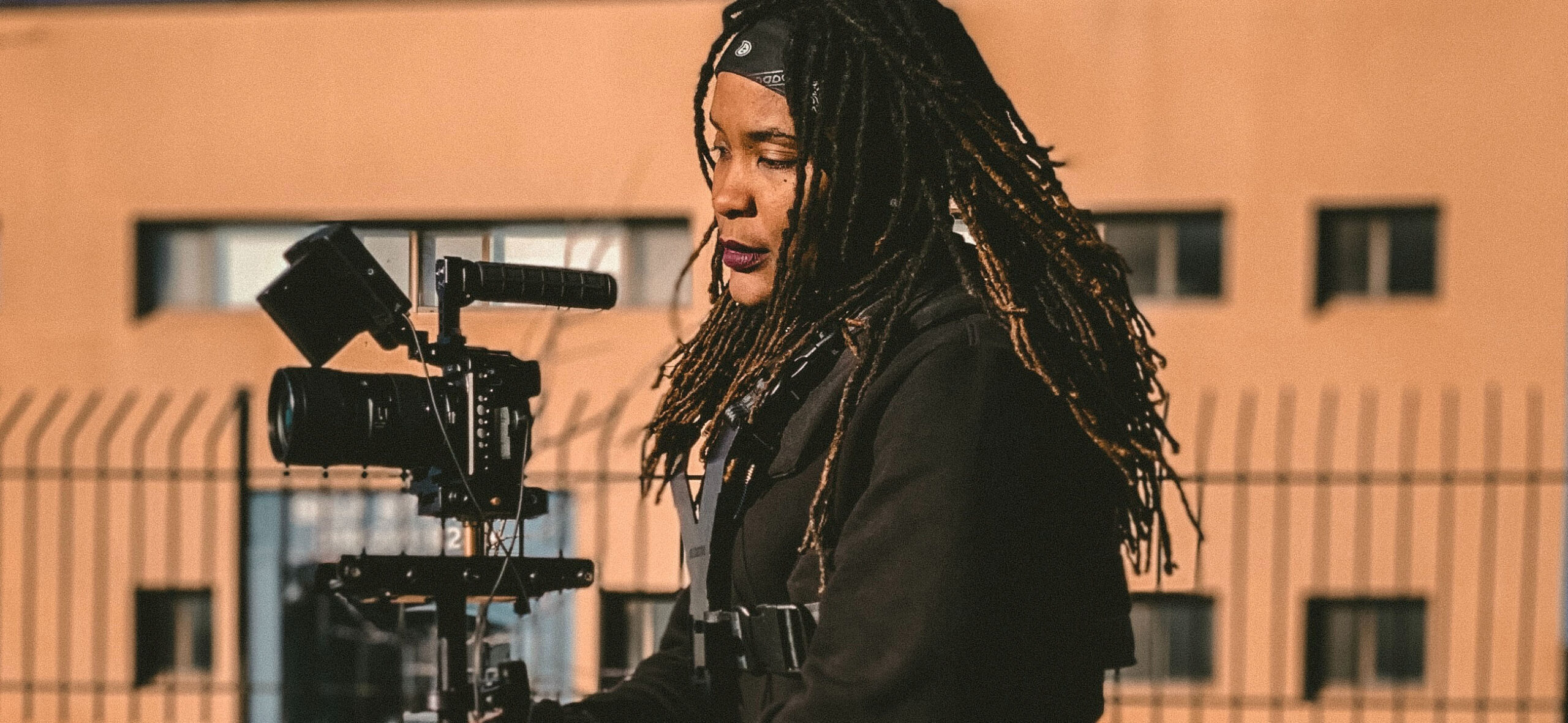 A Black woman on a set with a camera.