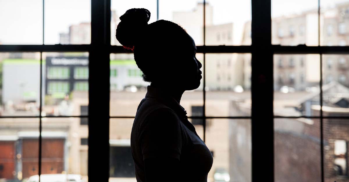 Silhouette of a woman against windows.