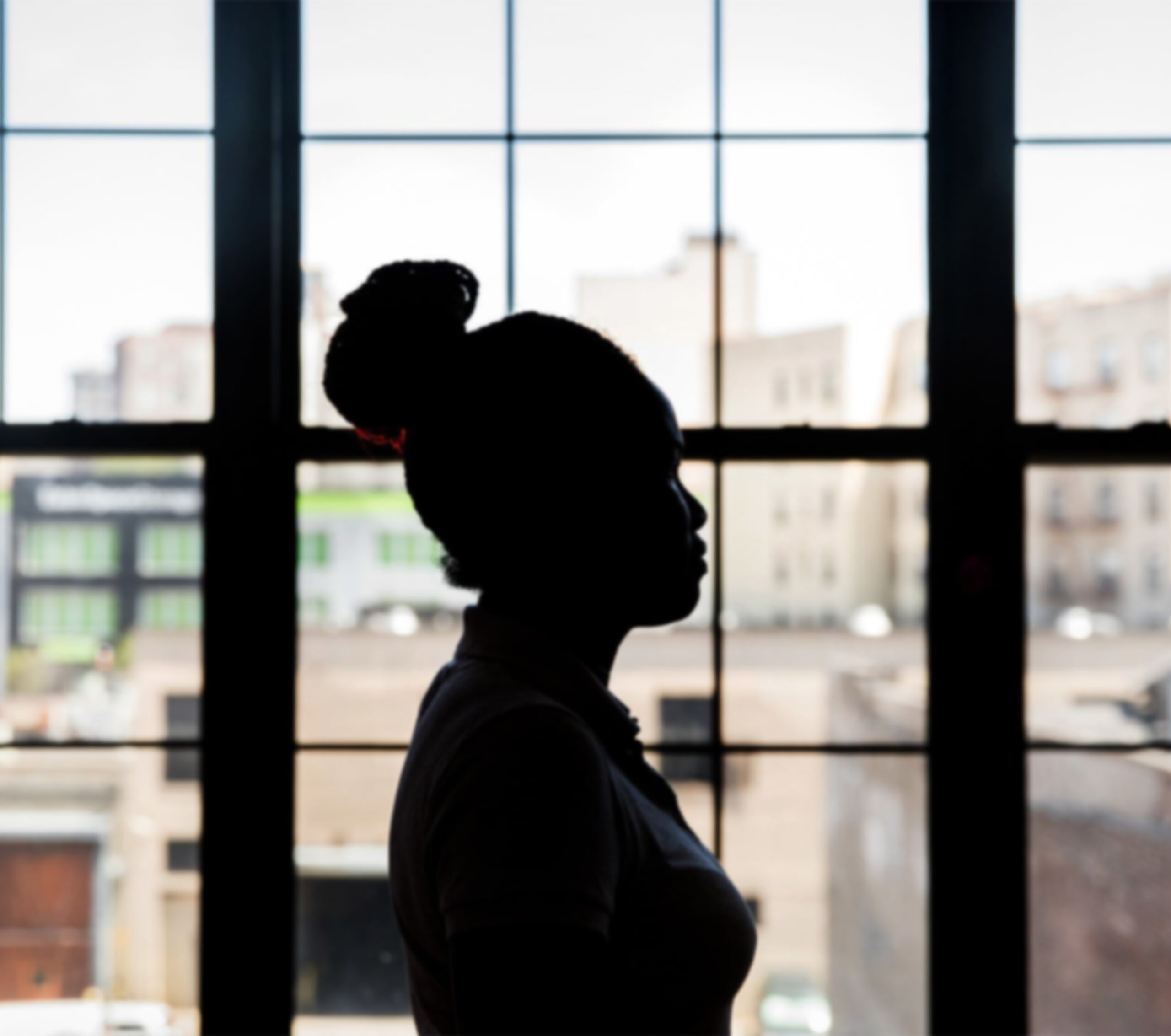 Silhouette of a woman against windows.